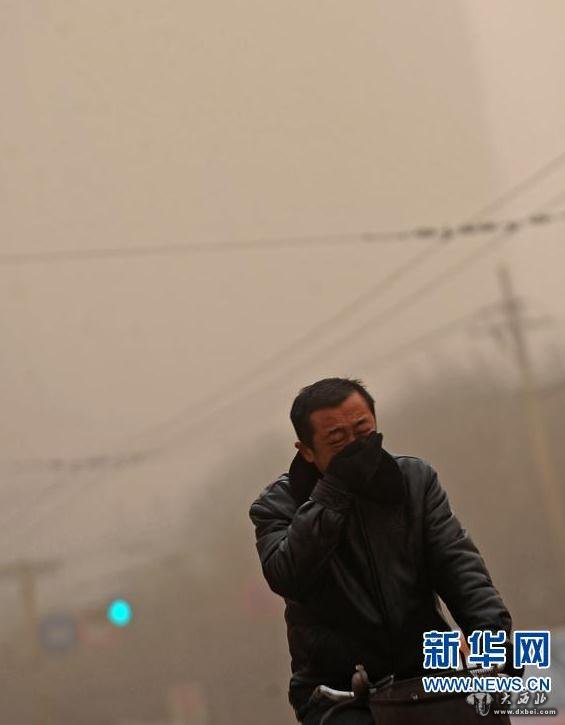 2月28日，在太原街頭，一位騎車人在沙塵暴中捂嘴前行。新華社記者范敏達(dá) 攝